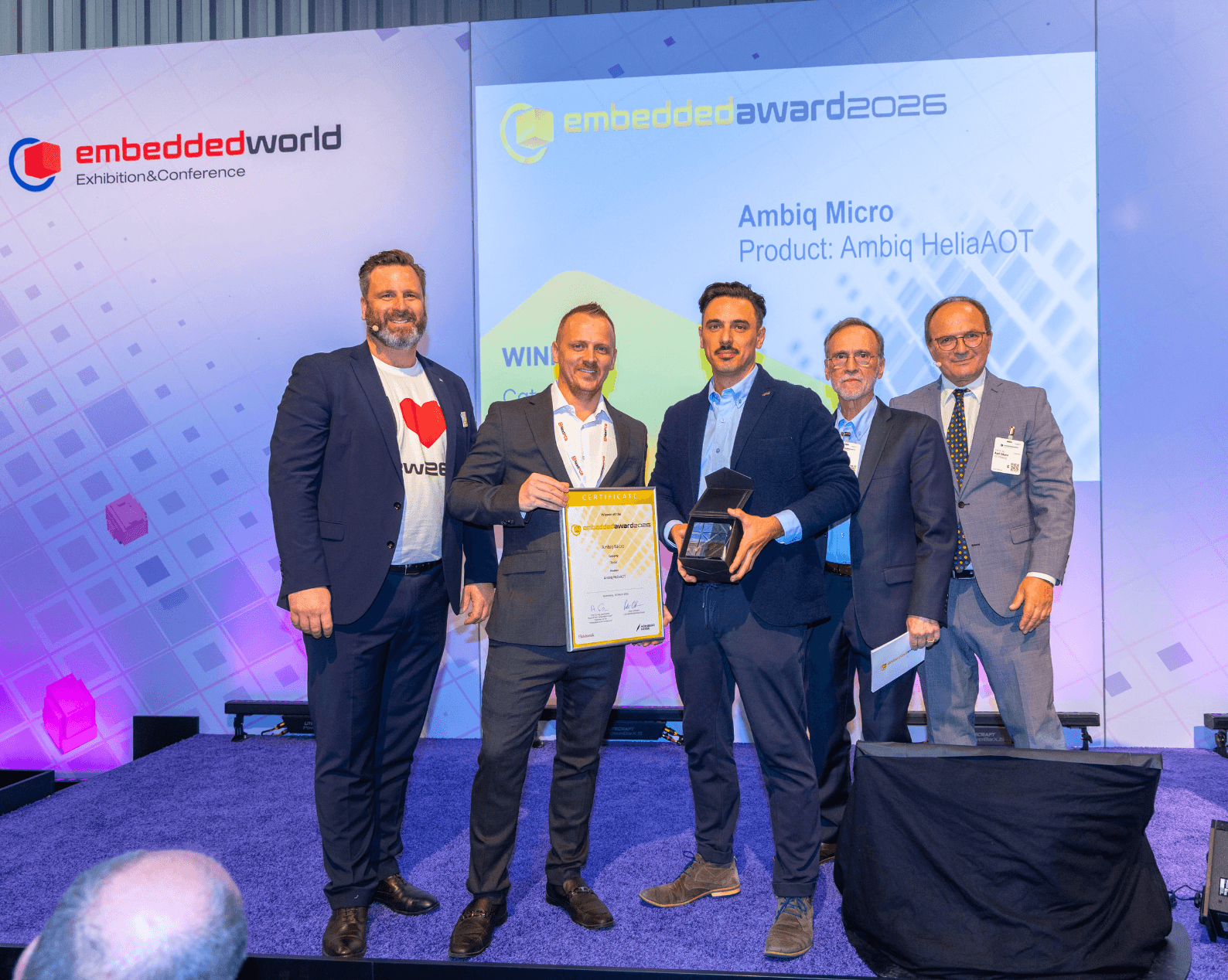 Fünf Männer in Businesskleidung mit Zertifikat und Glastrophäe auf der Award Bühne.