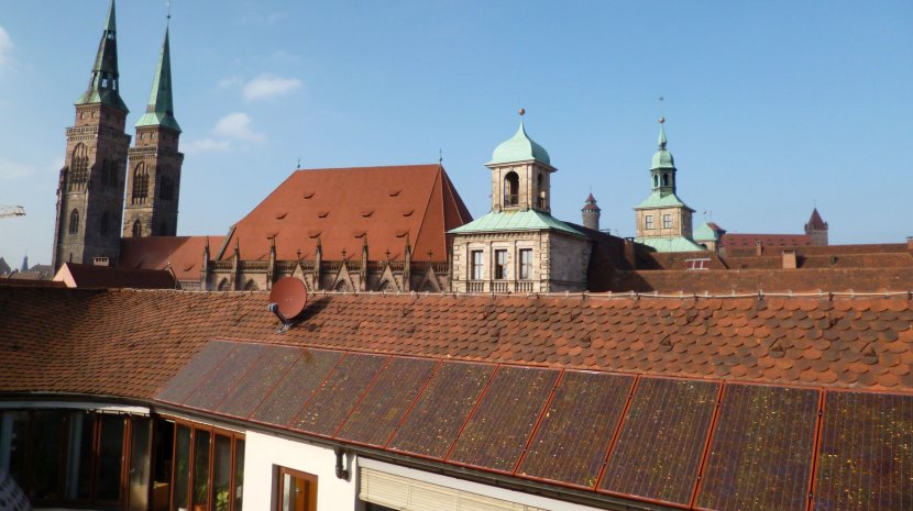 PV-Anlage mit roten Modulen auf dem denkmalgeschützten Rathaus am Hauptmarkt